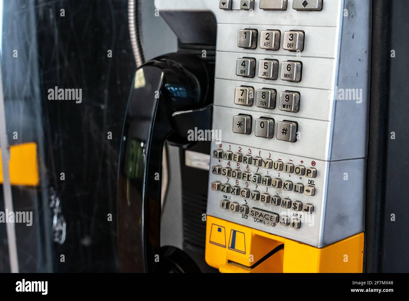 Ein altes verprügeltes Telefon in einem Einkaufszentrum im Südwesten von Ontario, Kanada. Schwarzer Empfänger, gelber Softfokus-Steckplatz für Kreditkarten. Silbernes Tastenfeld. Stockfoto