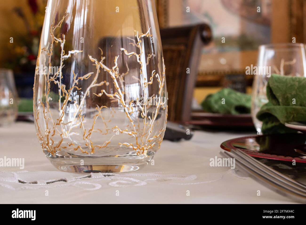 Ein stammloses Weinglas mit bemalten Gold- und Silberreben an den Seiten sitzt leer auf einem fein dekorierten Tisch in Erwartung eines Geburtstags-Abendessens. Feb Stockfoto