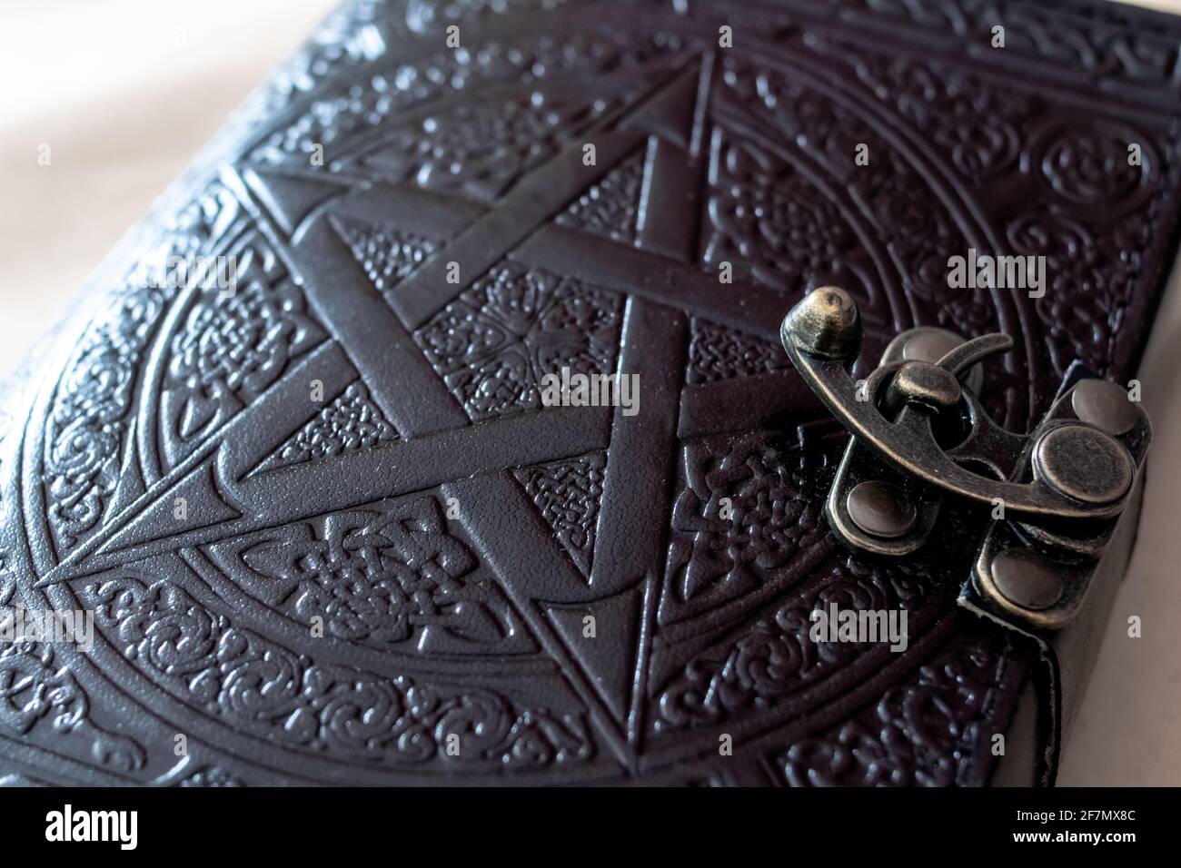 Nahaufnahme eines von Wicca inspirierten Journals mit einem Pentagramm auf der Vorderseite, geschlossen mit einer Metallschließe auf einem Hartholzschreibtisch, Ontario, Kanada. Stockfoto