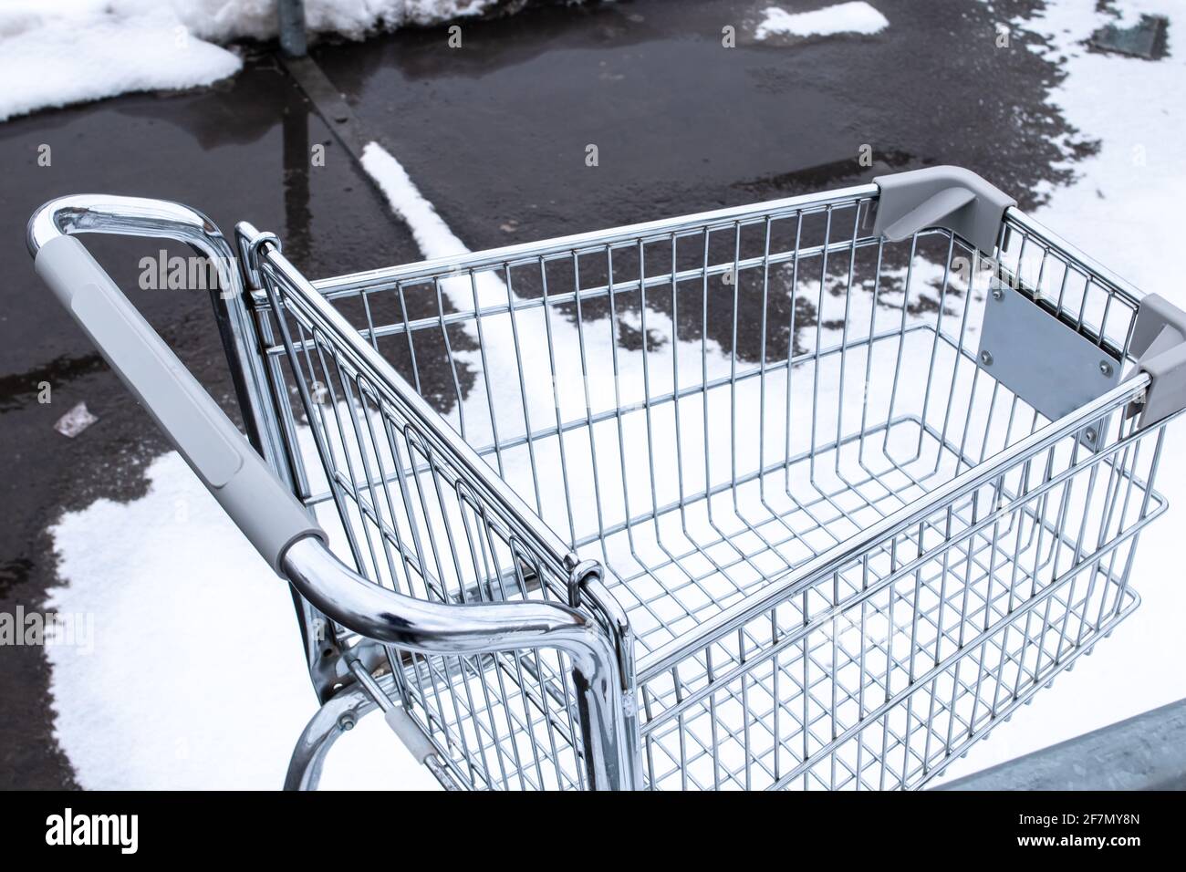 Ein silberner Einkaufswagen auf einem kargen Parkplatz mitten im Winter in London, Ontario, Kanada an einem trüben und bewölkten Tag. Stockfoto