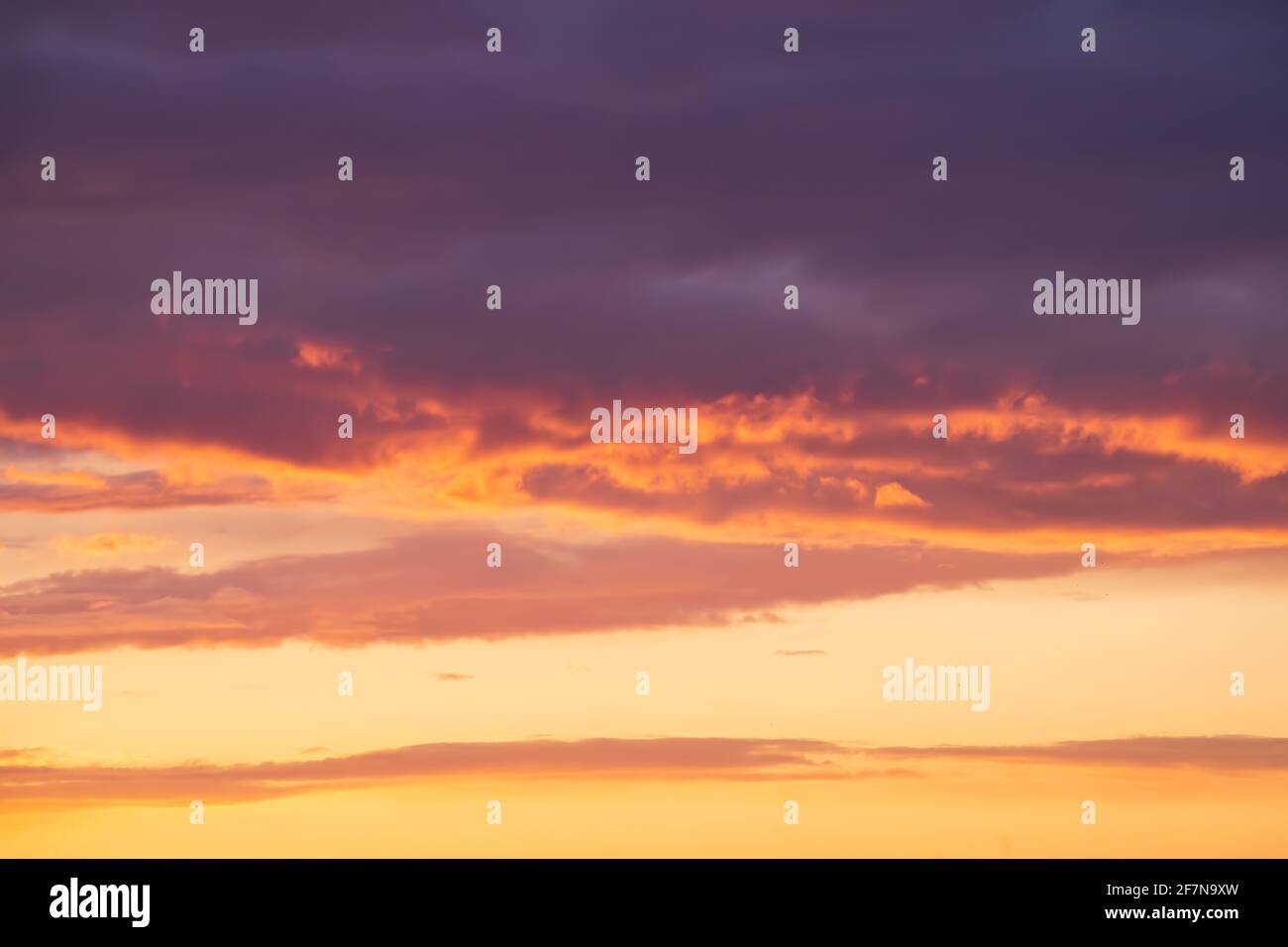Helle violette oder violette Wolken auf epischem orangefarbenem Sonnenuntergang am Himmel. Stockfoto