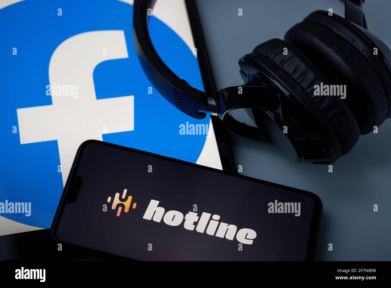 Logo der Hotline-App auf dem Smartphone mit Kopfhörern. Die Hotline-Plattform ist ein neuer Eintrag im Audio-Chat, der von Facebook, dem Konkurrenten des beliebten Clu, entwickelt wurde Stockfoto