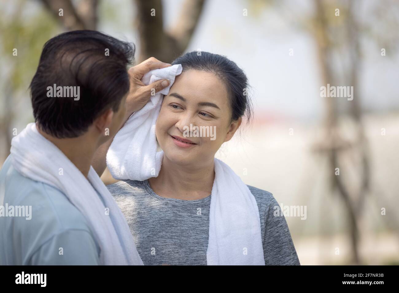 Der glückliche Ehemann des asiatischen Seniorenpaares wischte Schweiß vom Gesicht seiner Frau, nachdem er im Freiluftpark gelaufen war. Stockfoto