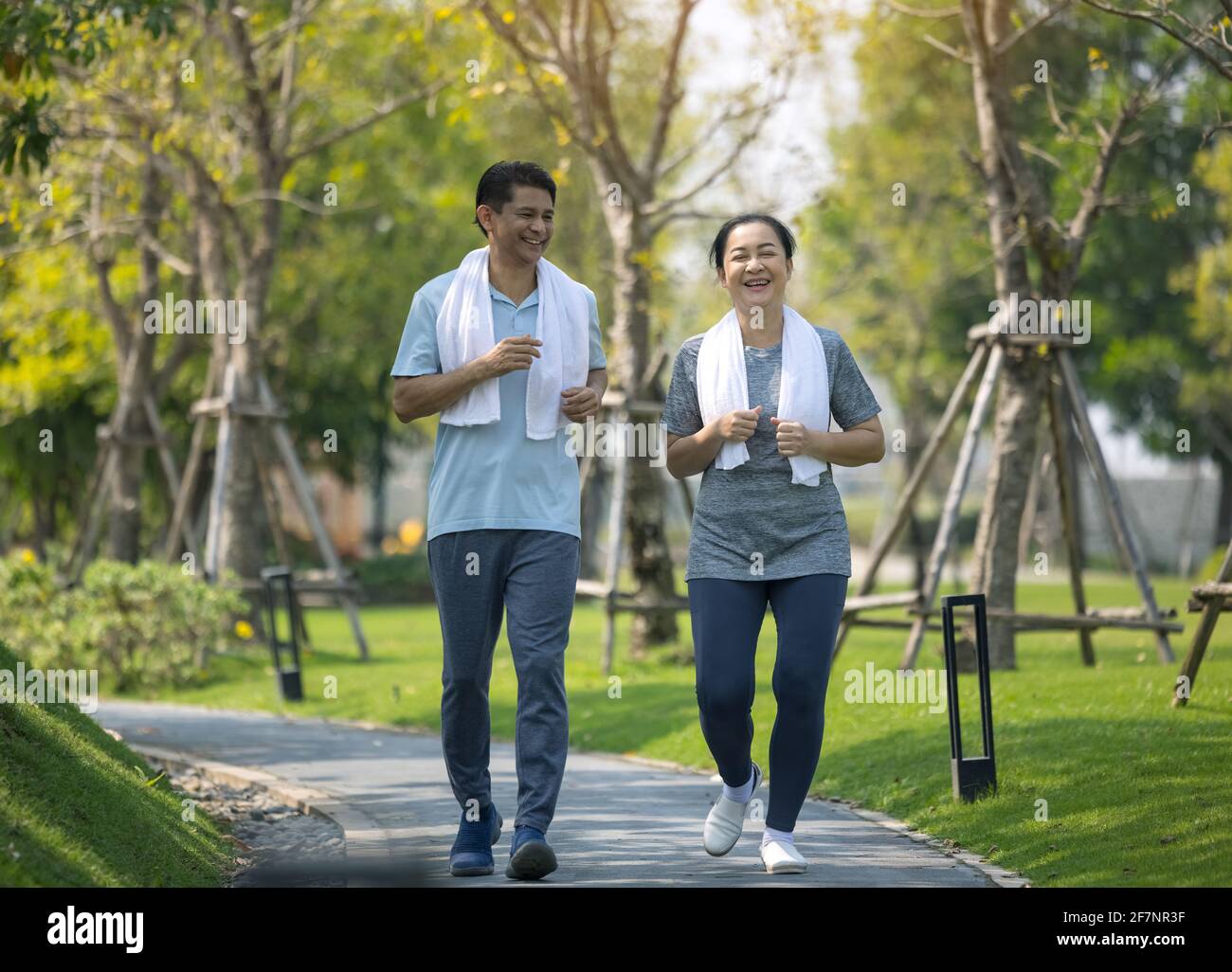 Lächelndes Seniorenpaar joggt, Seniorenpaar joggt und läuft im Park im Freien in der Natur Stockfoto