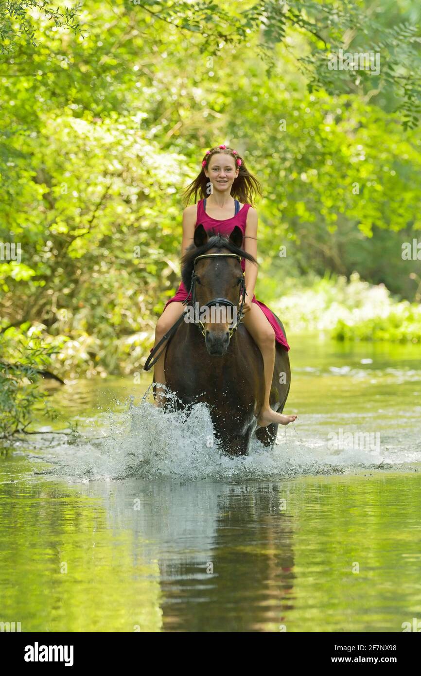 Mädchen auf der Rückseite des deutschen Ponys Reiten bareback in einem Streamen Stockfoto