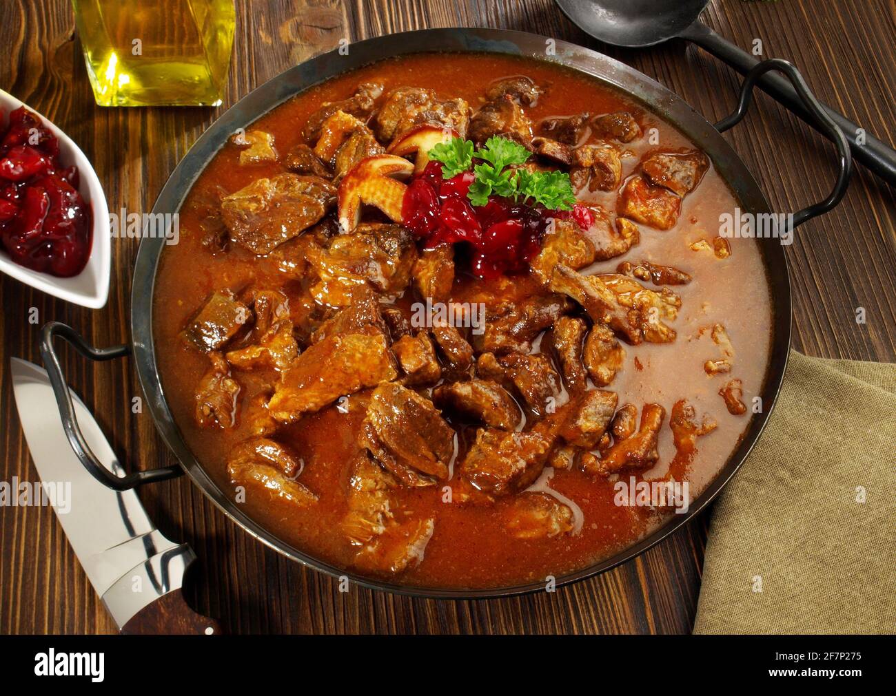 Wildfleisch Gulasch in einer Pfanne mit Cranberries auf Holzhintergrund Stockfoto