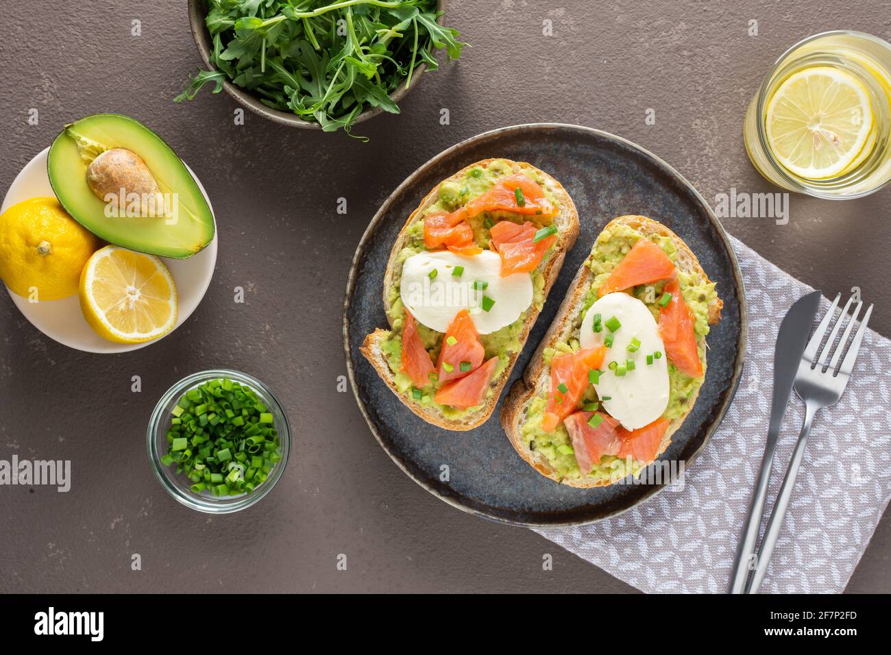 Leckeres herzhaftes Frühstück, Sandwiches mit Avocado-Paste, Lachs und Mozzarella auf einem Teller, Rucola und Erbsensprossen und grüne Zwiebel Stockfoto