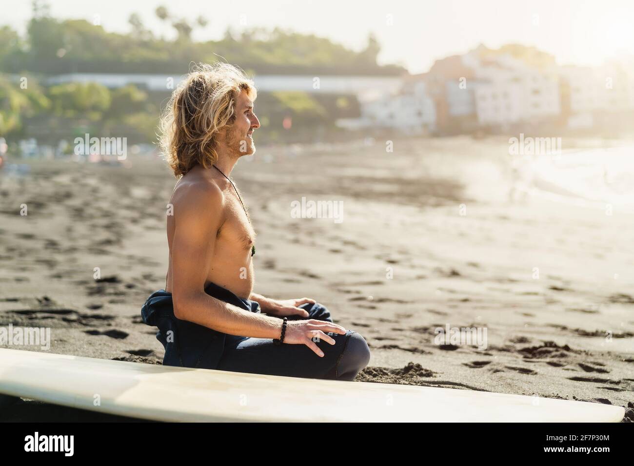 Junger Surfer auf Sand neben dem Surfbrett - Jugendliche surfen Kultur und Extremsport Lifestyle Konzept Stockfoto