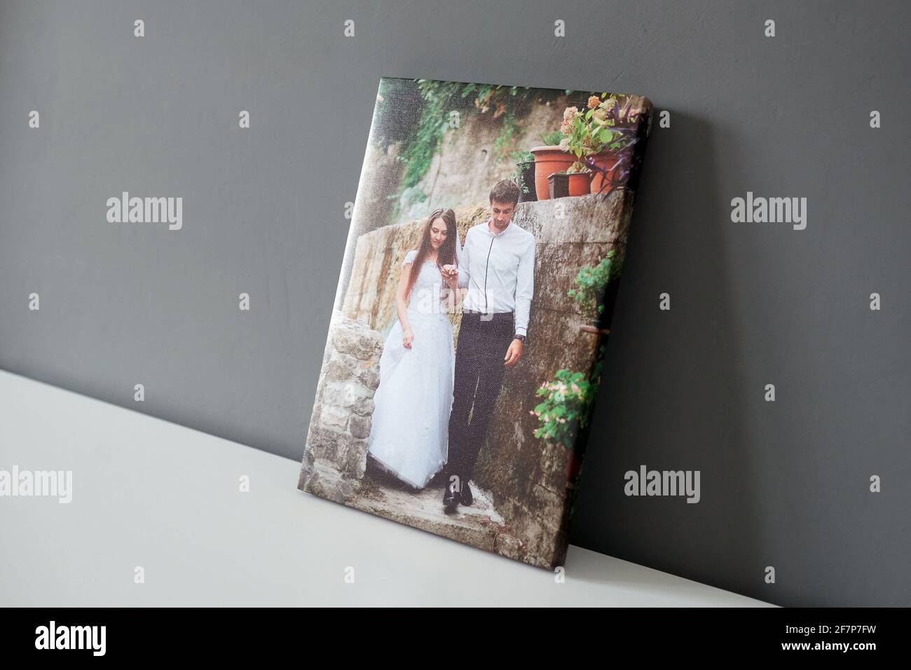 Hochzeitsfotografie mit Leinwanddruck auf weißem Tisch und grauem Wandhintergrund. Foto gedruckt auf Leinwand mit Galerie Umhüllung Stockfoto