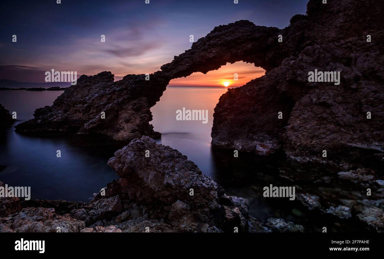 Sonnenaufgang über dem Meer durch den Steinbogen von Portitxol, in L'Escala, Alt Empordà (Costa Brava, Katalonien, Spanien) ESP: Amanecer en el mar a L'Escala Stockfoto