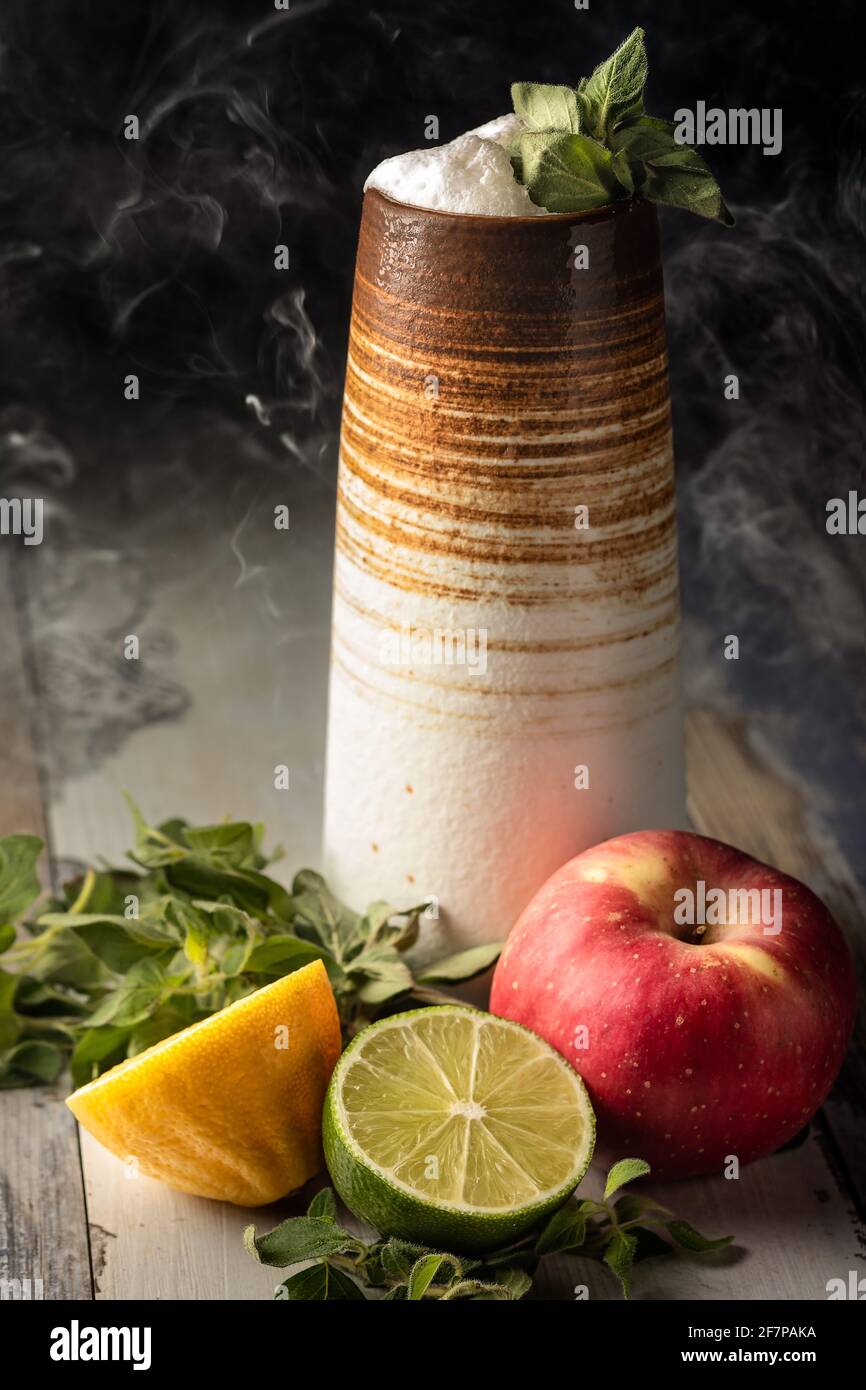 Schöner, langer, fruchtiger Cocktail aus frischer Limette, Apfel und Zitrone, serviert mit Salbei-Beilage und etwas Rauch Stockfoto