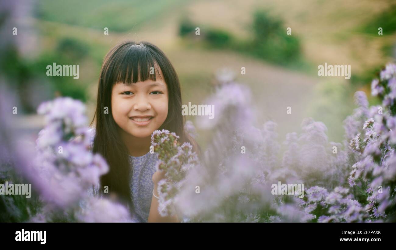 Asiatische kleines Kind Mädchen lächelt in Blumenfeldern Stockfoto
