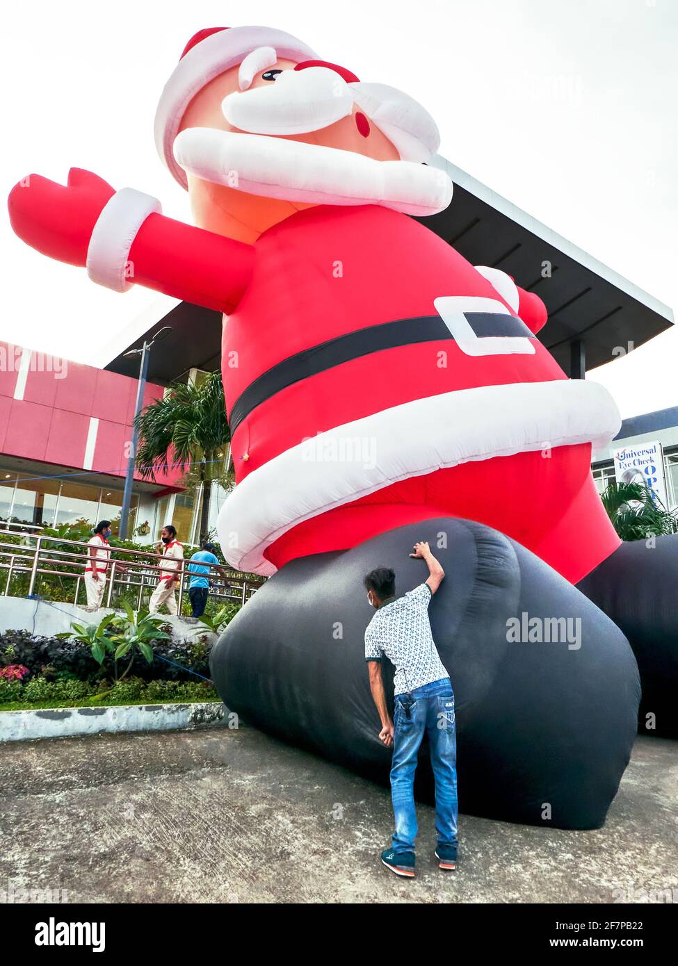 Der Mensch hält die Füße einer gigantisch aufblasbaren Weihnachtsmann-Verkaufsförderungsfigur vor der City Mall, Boracay Island, Philippinen, Asien Stockfoto