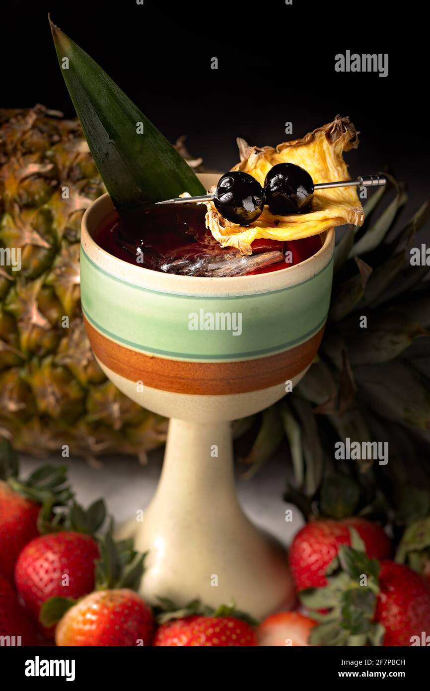 Ananas- und Erdbeeren-Wodka-Cocktail in einer interessanten Tasse, mit Eis und einer schönen Ananasgarnitur. Stockfoto