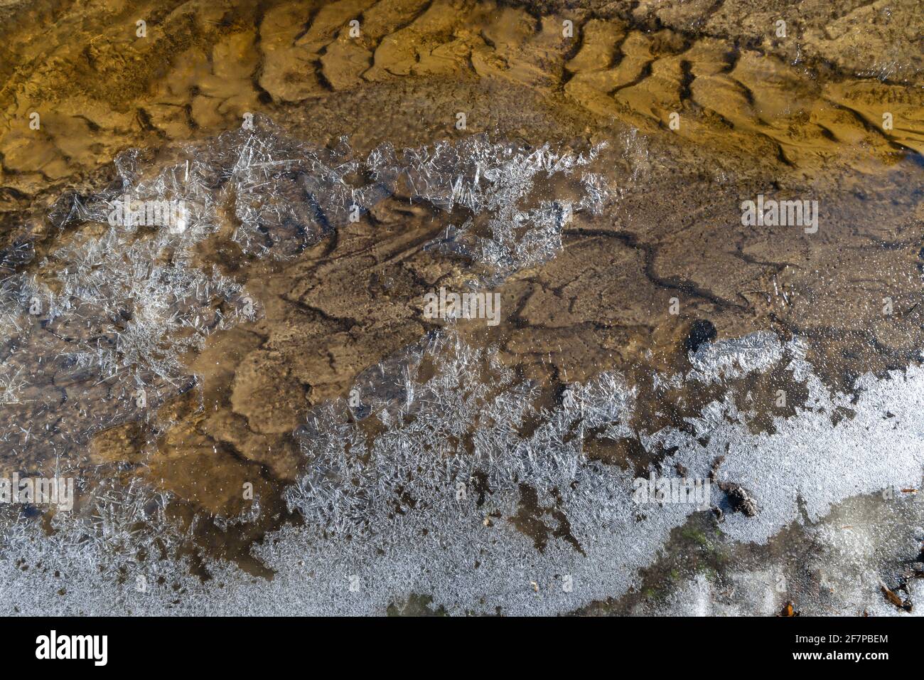 Kurve der gemusterten Streambed und der Eiskruste an Der Rand der Strömung an einem Frühlingsmorgen Stockfoto