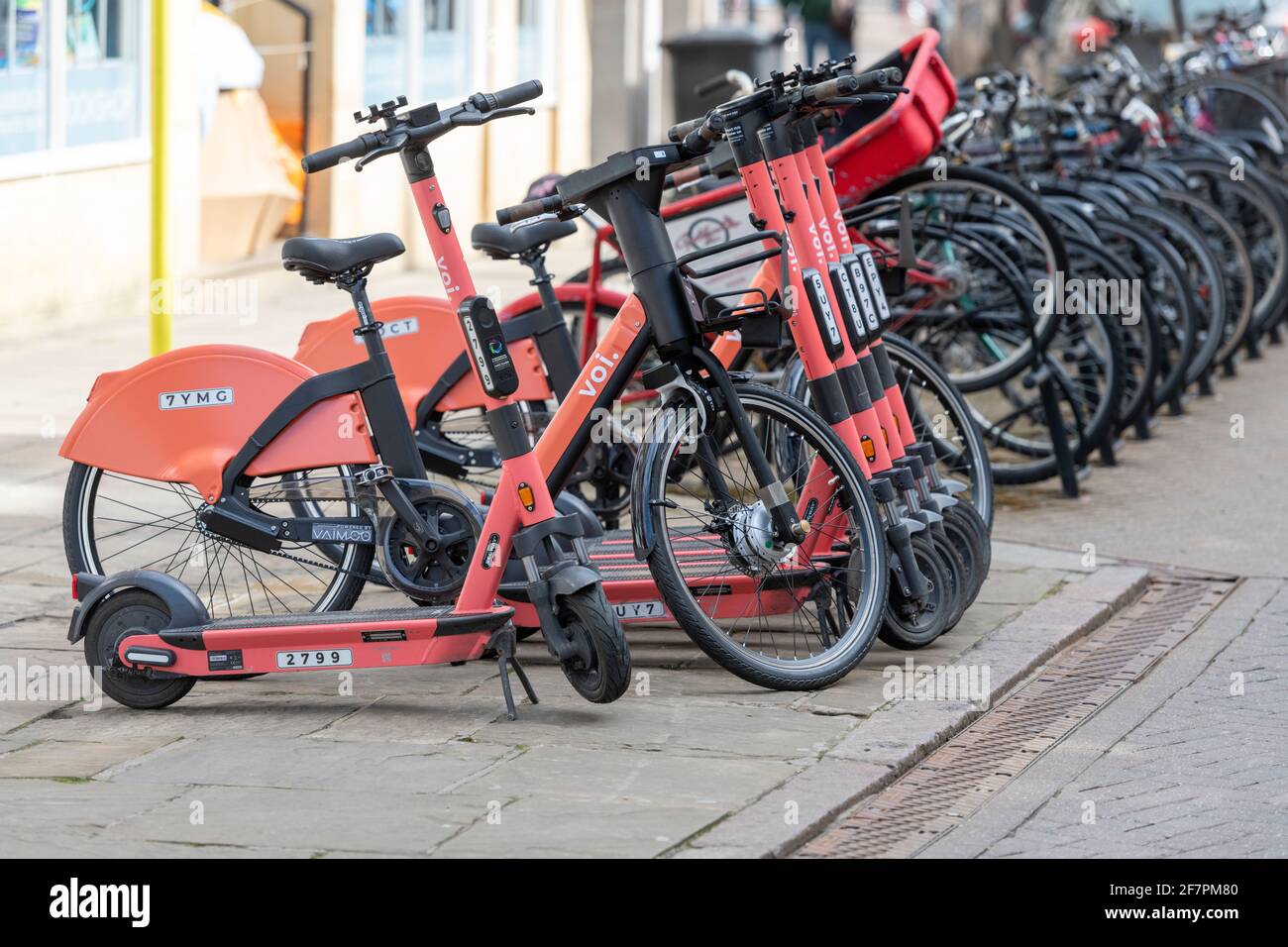 VOI-Elektrofahrräder und -Roller, die bei einer Sammlung geparkt sind Point for hire in Cambridge UK Stockfoto
