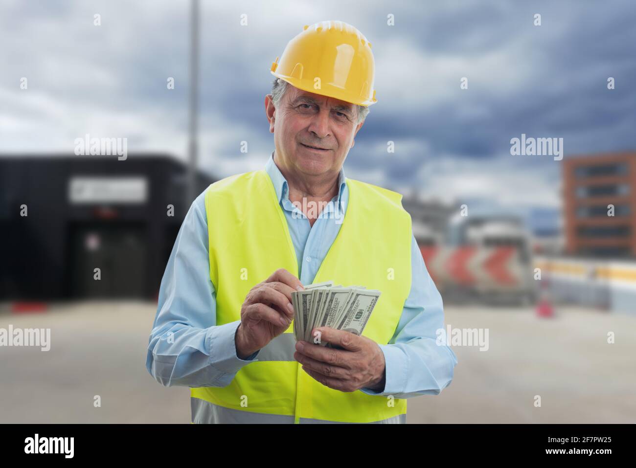Ältere männliche Bauarbeiter tragen gelben Schutzhardhut und arbeiten Weste Zählen von Bargeldern als Gehaltszahlungskonzept mit Aufbau Standort Stockfoto