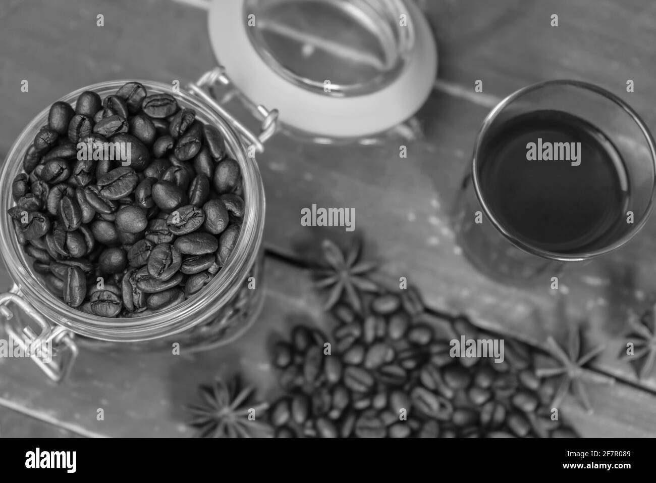 Draufsicht schwarzer amerikanischer Kaffee im Glas mit gerösteten Kaffeebohnen im Glas auf rustikalem Holztisch.Schwarz-Weiß-Fotografie, Kaffee Vintage Hintergrund Stockfoto