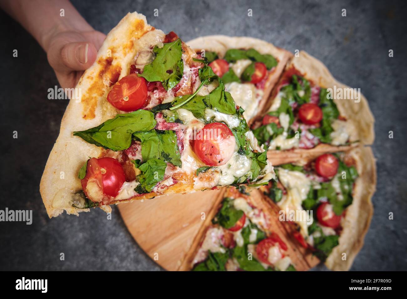 Pizza mit Käse, Tomaten, Spinat und Räucherwurst Stockfoto