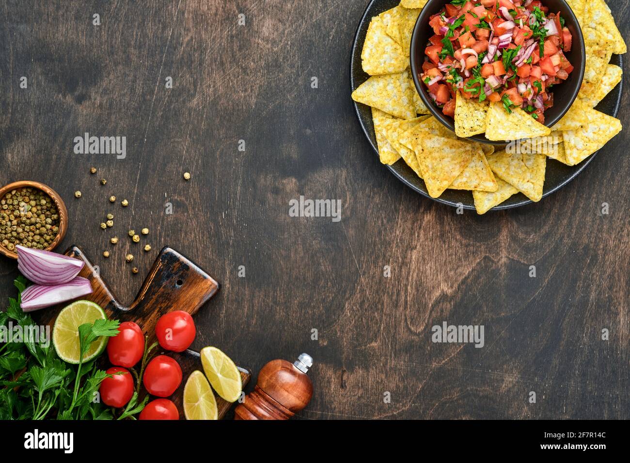 Traditionelle mexikanische Tomatensauce Salsa mit Nachos und Zutaten Tomaten, chile, Knoblauch, Zwiebel auf dunklem alten Holzhintergrund. Konzept der lateinischen Amer Stockfoto