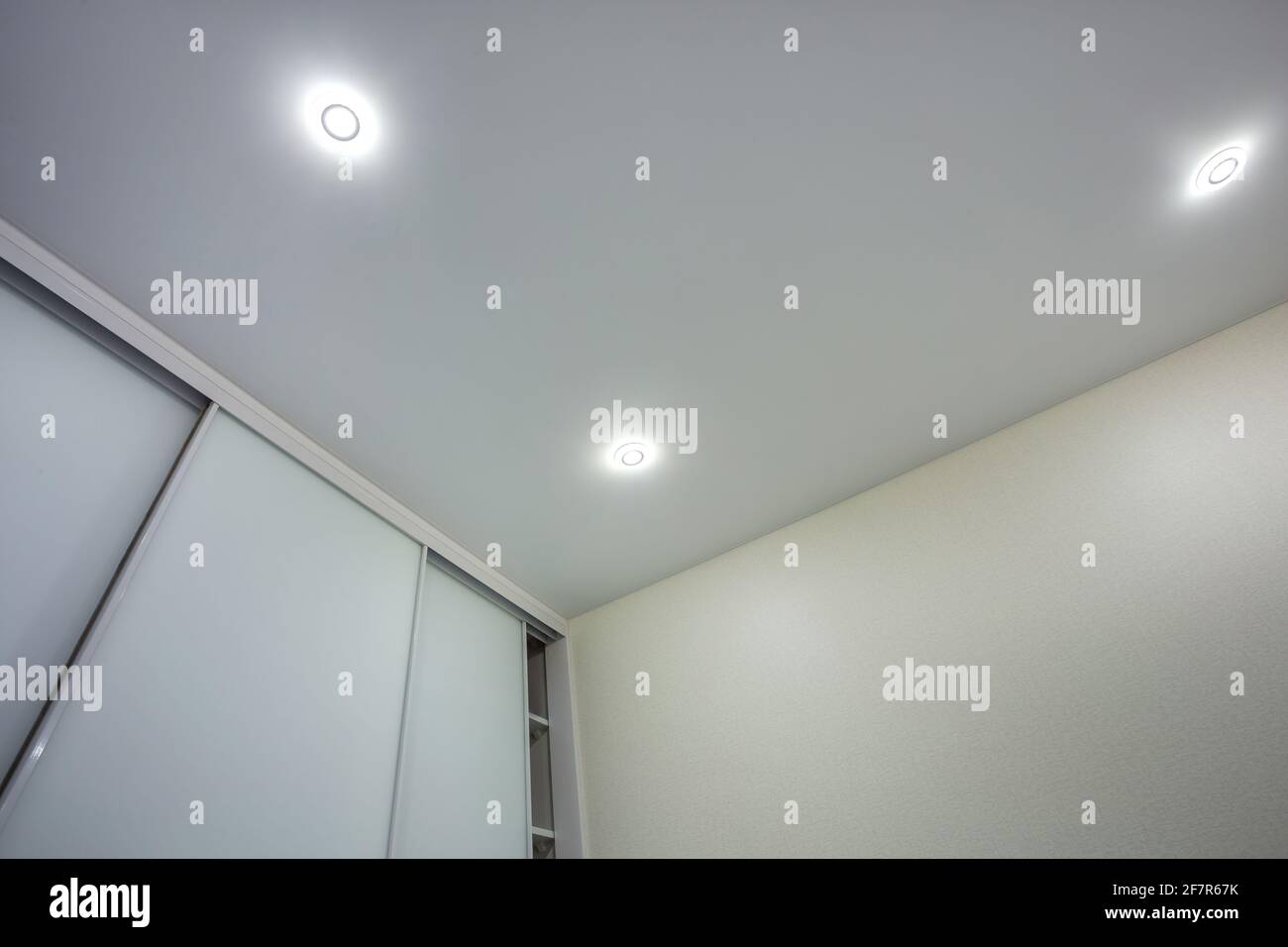 Abgehängte Decke mit Halogenstrahlern und Trockenmauerkonstruktion im leeren Raum in Wohnung oder Haus. Stretchdecke weiß und komplex. Stockfoto