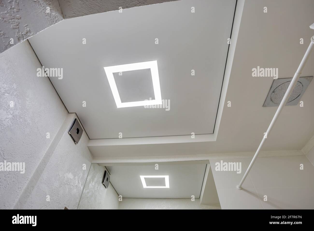 Abgehängte Decke mit Halogenstrahlern und Trockenmauerkonstruktion im leeren Raum in Wohnung oder Haus. Stretchdecke weiß und komplex. Stockfoto