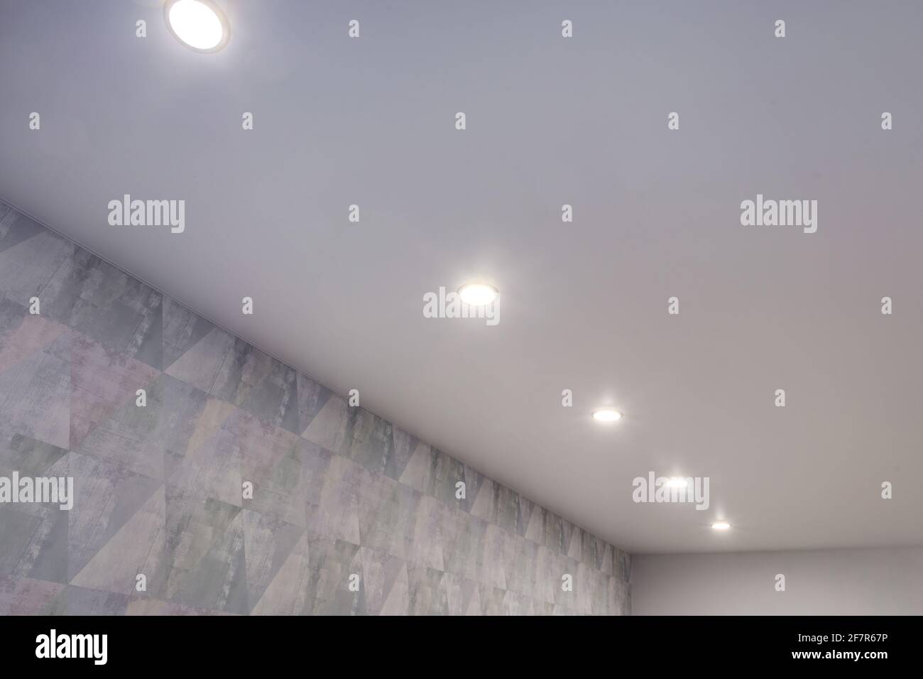Abgehängte Decke mit Halogenstrahlern und Trockenmauerkonstruktion im leeren Raum in Wohnung oder Haus. Stretchdecke weiß und komplex. Stockfoto