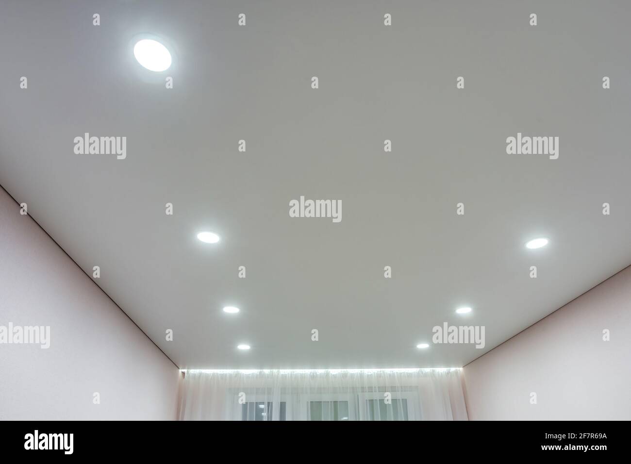 Abgehängte Decke mit Halogenstrahlern und Trockenmauerkonstruktion im leeren Raum in Wohnung oder Haus. Stretchdecke weiß und komplex. Stockfoto