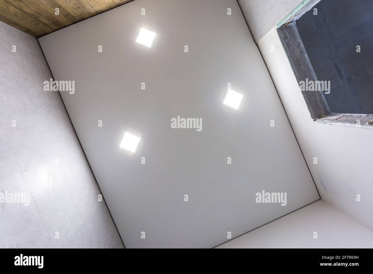 Abgehängte Decke mit Halogenstrahlern und Trockenmauerkonstruktion im leeren Raum in Wohnung oder Haus. Stretchdecke weiß und komplex. Stockfoto
