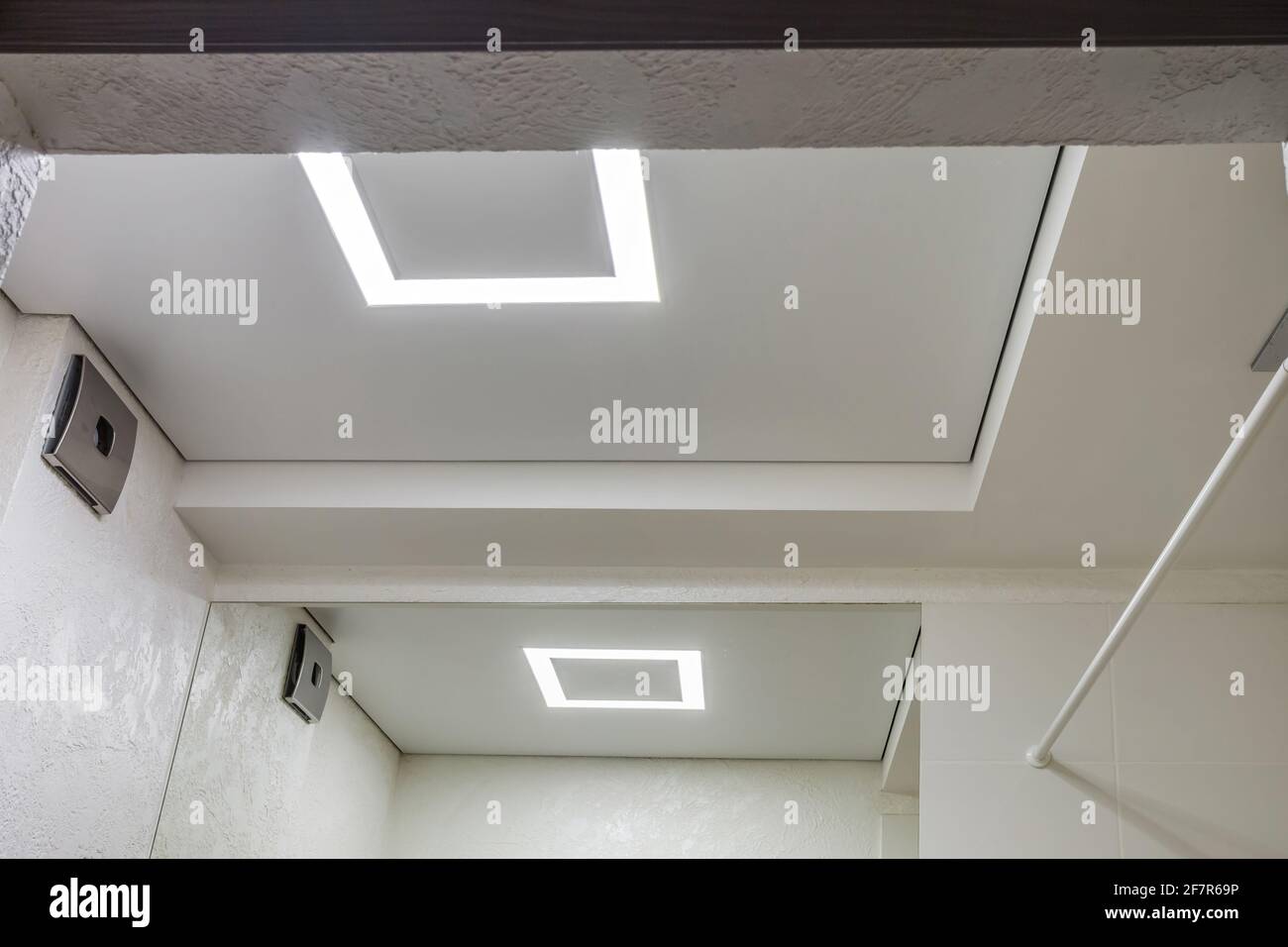 Abgehängte Decke mit Halogenstrahlern und Trockenmauerkonstruktion im leeren Raum in Wohnung oder Haus. Stretchdecke weiß und komplex. Stockfoto