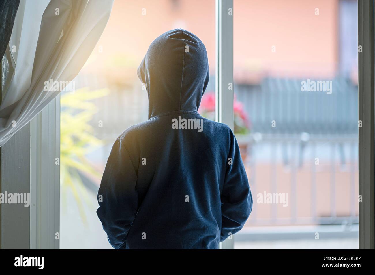 Kind von hinten gesehen, das zum Fenster blickt, ist unmöglich zu gehen Während des Shutdown-Zeitraums wird die Wiedergabe beendet Stockfoto