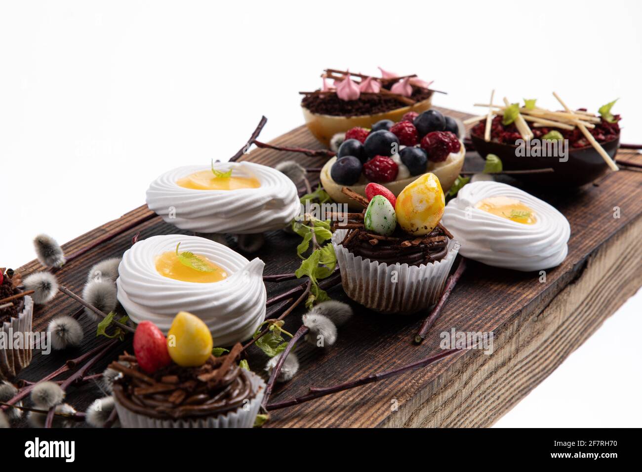 Auswahl an verschiedenen süßen Cupcakes, Keksen und gefüllten Schokoladeneiern auf Holzbrett Stockfoto