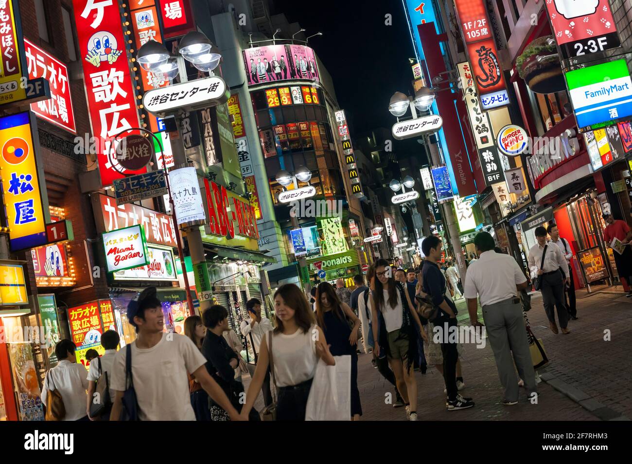 Horizontale schräge Ansicht der Menge, die bei Nacht durch die bunten Neonschilder am Shibuya Center-gai, Shibuya, Tokio, Japan, schlendert Stockfoto