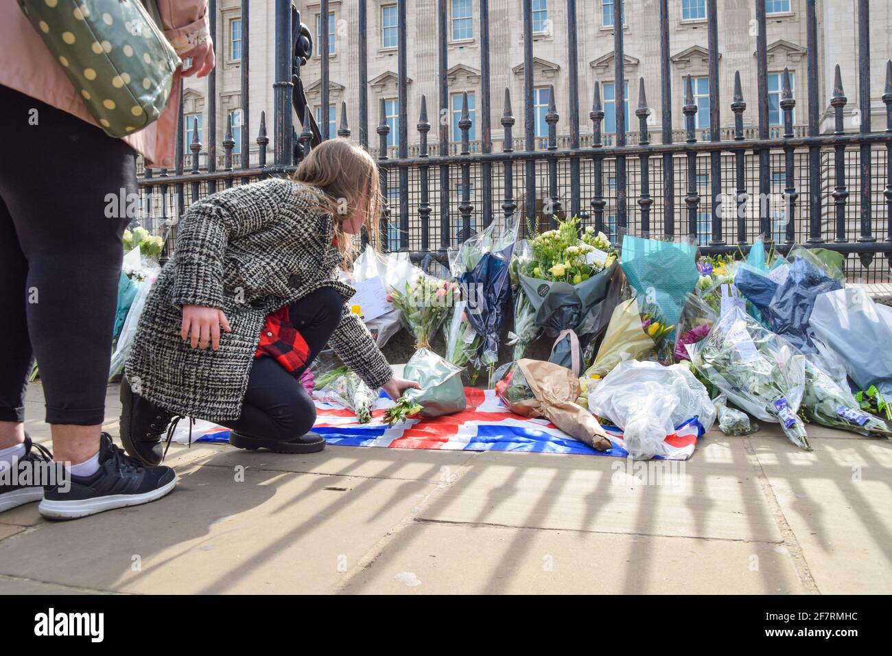 London, Großbritannien. April 2021. Ein Mädchen legt Blumen zu Ehren von Prinz Philip vor dem Buckingham Palace. Der Herzog von Edinburgh starb heute im Alter von 99 Jahren. Kredit: Vuk Valcic/Alamy Live Nachrichten Stockfoto