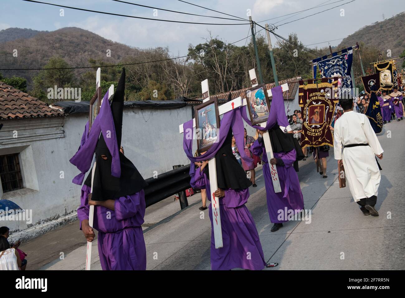 Die Bußen mit Kapuze tragen Kreuze während der Semana Santa Prozession in Antigua, Guatemala, eine feierliche Fastentradition, die die Passion Christi widerspiegelt. Stockfoto