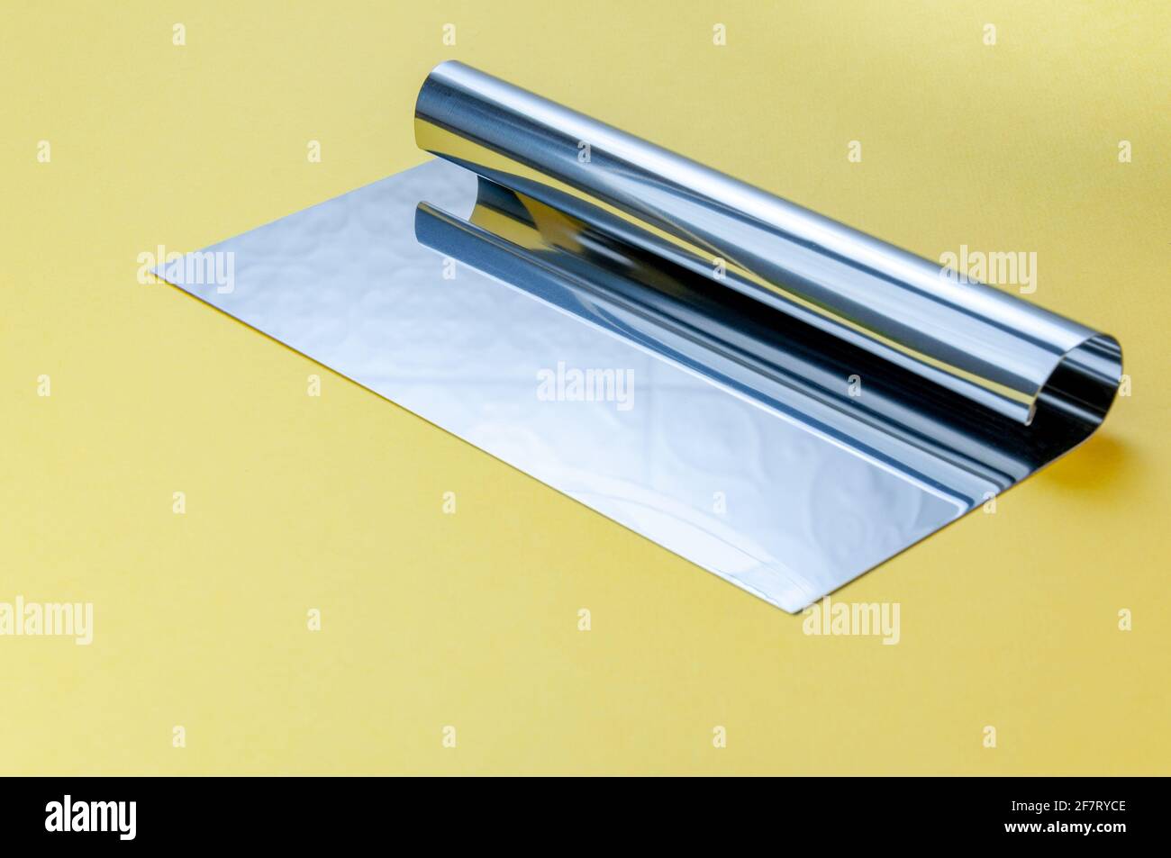 Metall-Teig Schaber Messer über hellgelben Oberfläche Hintergrund. Flacher Teigschaber aus Edelstahl Stockfoto