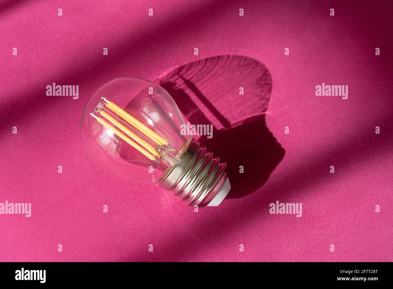Glühlampe auf violettem Hintergrund mit Nahaufnahme der Schatten. Kreative neue Idee, Innovation, Inspirationskonzept. Stockfoto