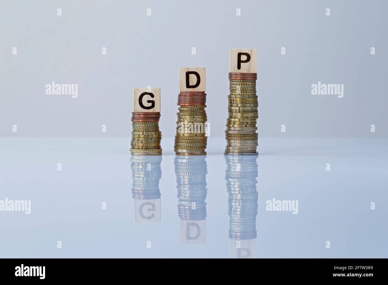 Wort „GDP“ auf Holzblöcken auf aufsteigenden Münzstapeln auf Grau. Konzeptfoto des Wirtschaftsindikators des Bruttoinlandsprodukts, der Wirtschaft und des Wohlstands. Stockfoto