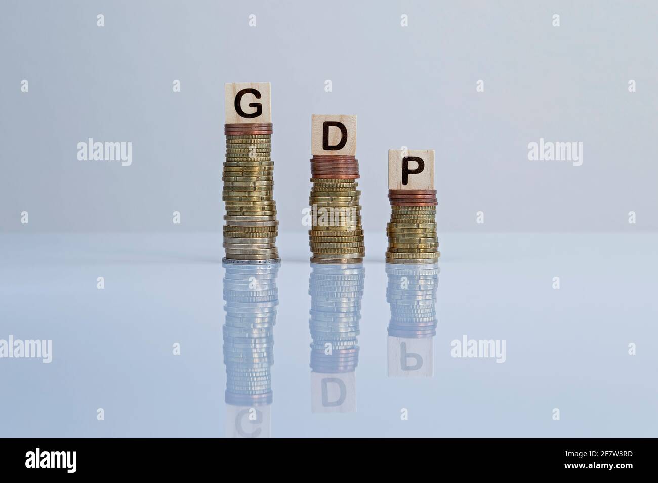 Wort „GDP“ auf Holzblöcken auf absteigenden Münzstapeln. Konzeptfoto des BIP (Bruttoinlandsprodukt) Konjunkturindikator, Wirtschaft und Rezession. Stockfoto