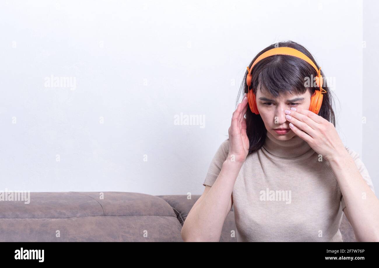 Porträt einer frustrierten Frau, die auf einem Mobiltelefon Musik hört und zu Hause ihre Tränen auswischt. Frau verärgert nach Online-Kommunikation zu Hause, Stockfoto
