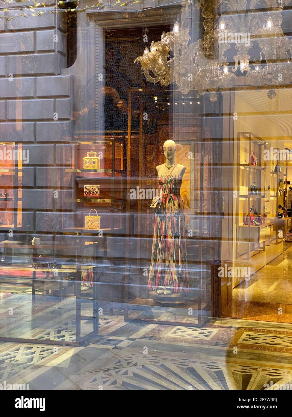 Spiegelung einer Person, die vor dem Fenster eines großen Modehauses läuft, das wegen des Covid-19 geschlossen wurde. Durch das Fenster können wir ein Mannequin sehen Stockfoto
