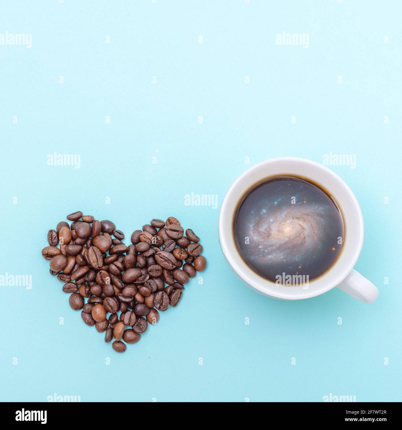 Tasse schwarzen Kaffee mit Schaumstoff in Form einer Galaxie, Kaffeekörner in Form eines Herzens auf blauem Hintergrund, Kopierraum, Draufsicht, quadratische Form. Stockfoto