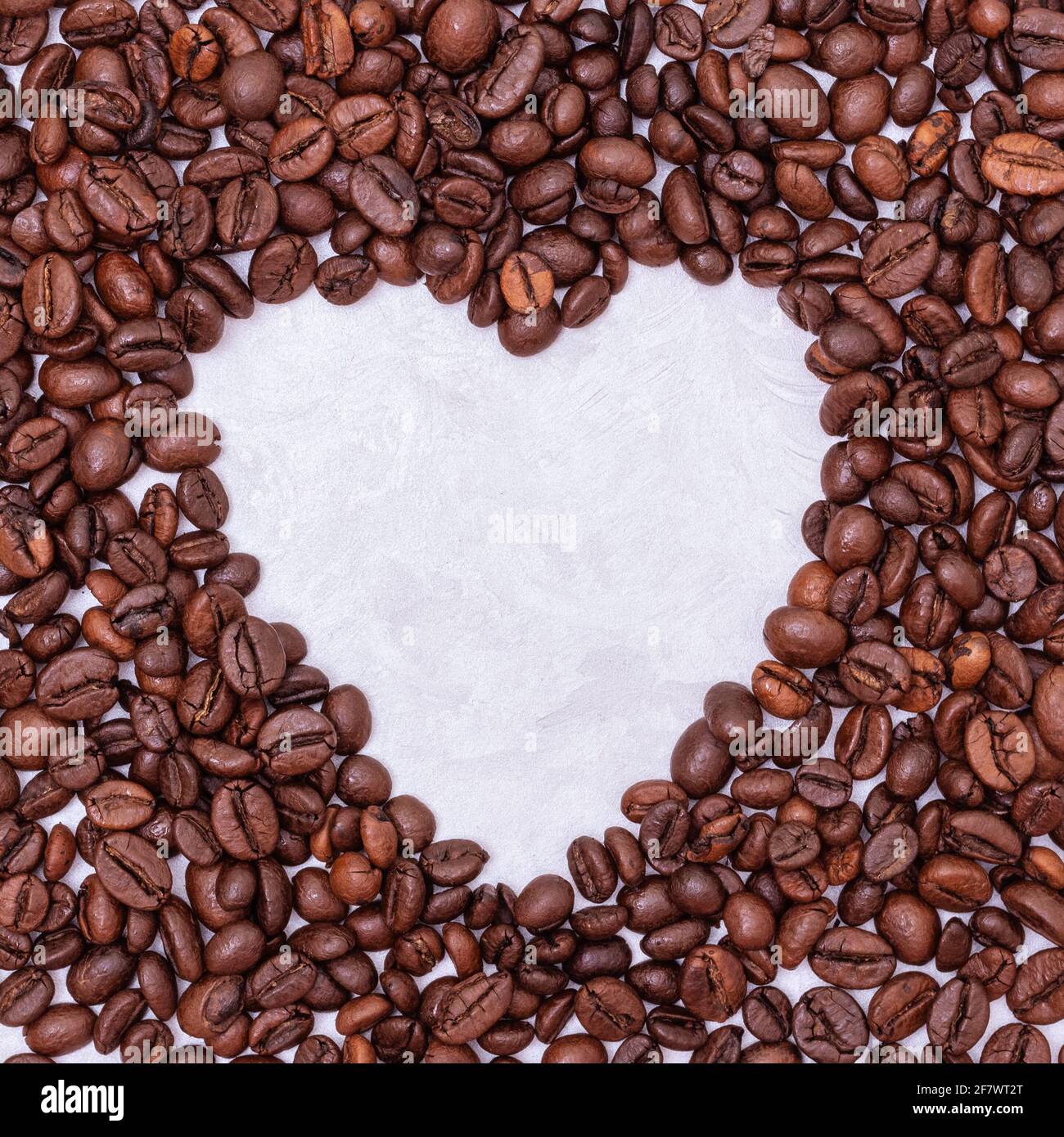 Herz-Kaffeestahmens aus Kaffeebohnen auf weißem Stuckhintergrund, Draufsicht, Kopierraum. Kaffee Liebe Konzept. Stockfoto