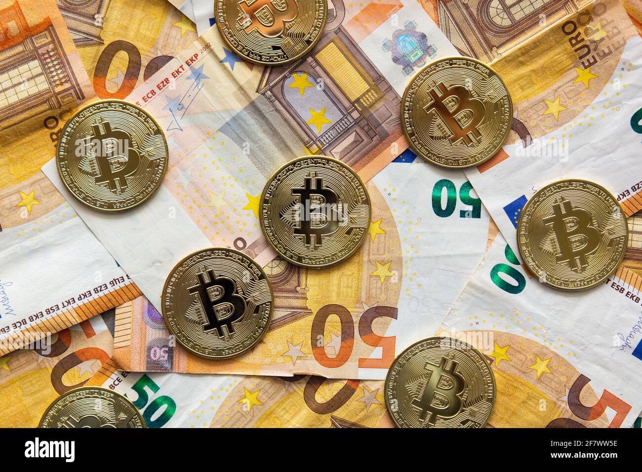 Overhead-Ansicht einiger Bitcoins auf einem Hintergrund von 50-Euro-Scheinen. Bitcoin als neues Geld, Börse von Kryptowährungen und dezentrale Finanzen con Stockfoto