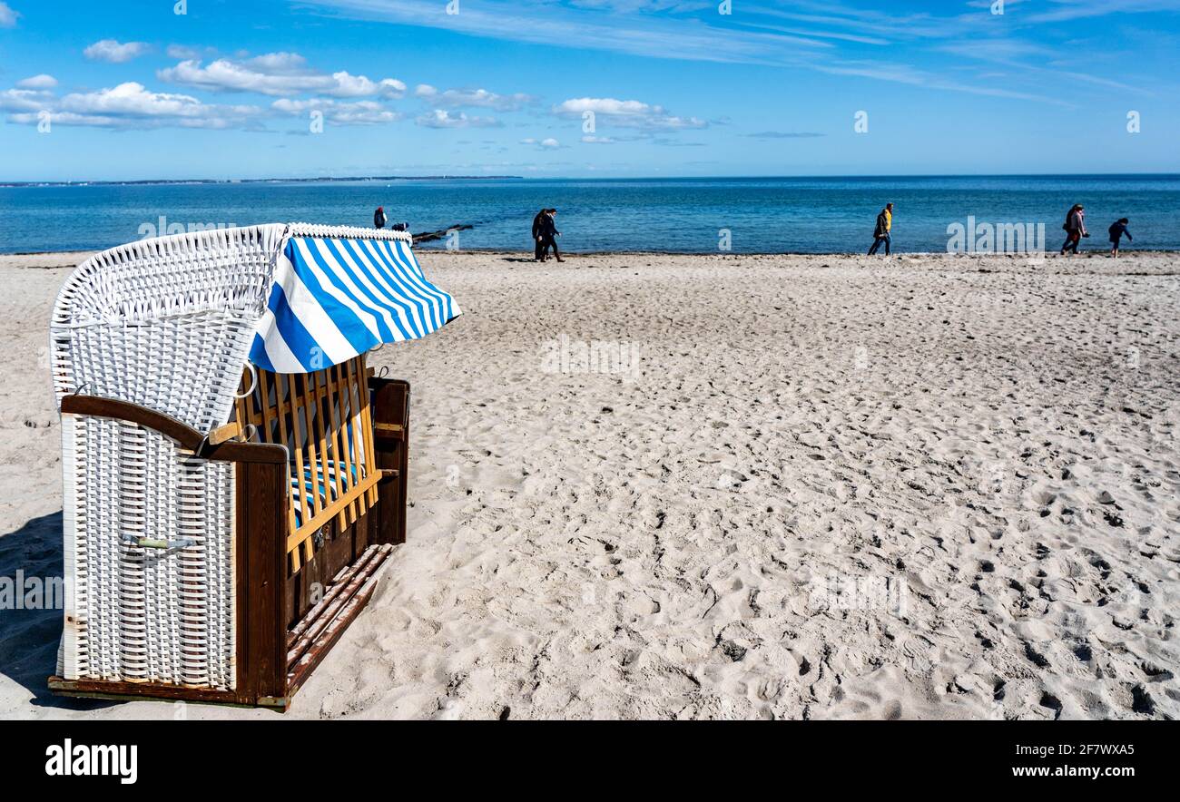 Timmendorfer Strand, Deutschland. April 2021. Hinter den ersten Strandliegen am Timmendorfer Strand laufen die Menschen in strahlendem Sonnenschein am Ufer der Ostsee entlang. Quelle: Axel Heimken/dpa/Alamy Live News Stockfoto