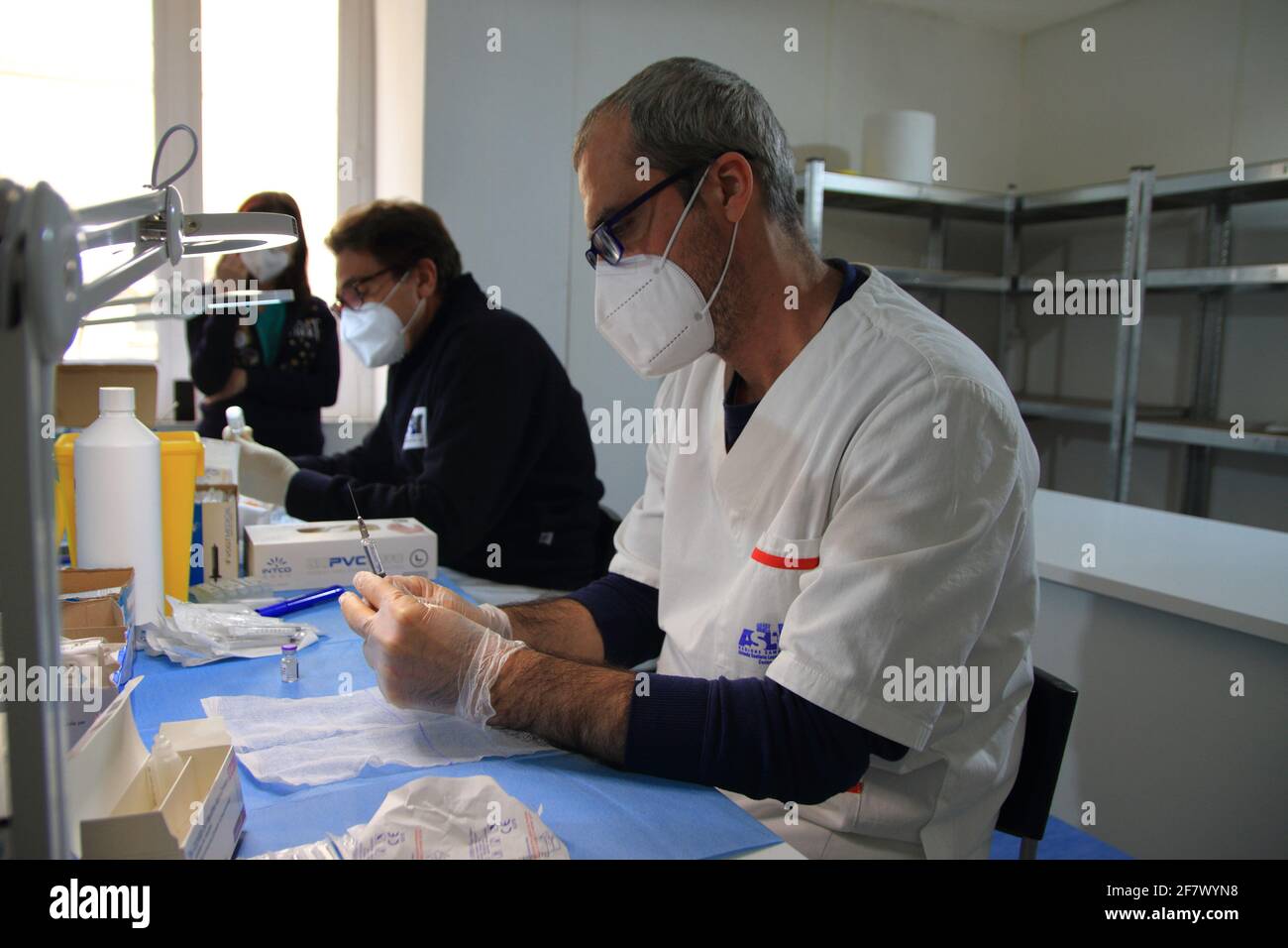 Krankenschwestern in der Apotheke bereiten unter Anleitung eines Arztes Spritzen mit Dosen von pfizer-biontech-Impfstoff oder astrazeneca vor. Stockfoto