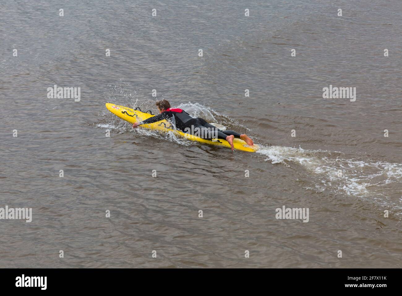 Bournemouth, Dorset, Großbritannien. April 2021. Das Wetter in Großbritannien: Kühl, bewölkt und grau, nur wenige Menschen gehen zum Meer an den Stränden von Bournemouth, um sich zu bewegen. RNLI Lifeguard Tim trainiert auf seinem Surfbrett, um sich auf eine geschäftige Saison im Meer vorzubereiten. Quelle: Carolyn Jenkins/Alamy Live News Stockfoto