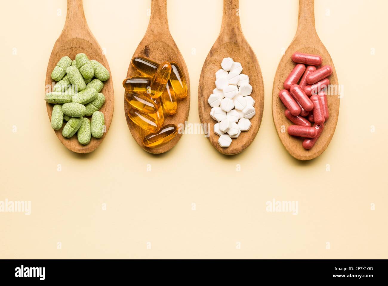 Mischung von Supplement Pillen auf Holzlöffel auf gelbem Hintergrund Stockfoto