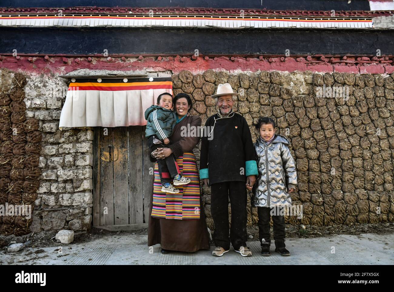 (210410) -- LHASA, 10. April 2021 (Xinhua) -- Dawa Gokye und seine Familienmitglieder posieren für ein Foto vor ihrem Wohnsitz im Dorf Gyadu der Gemeinde Jangra im Kreis Gyangze der Stadt Xigaze, südwestlich der Autonomen Region Tibet, 22. März 2021. Dawa Gokye, 76, einst Leibeigene in einem lokalen Herrenhaus Tibets, lebte bis zur demokratischen Reform 1959 in Hoffnungslosigkeit und Verzweiflung. In den Augen der Leibeigenen sind Leibeigene nichts anderes als "sprechende Werkzeuge", die ihnen ausgeliefert sind. Dawa erinnerte sich, dass sein Kopf vom Verwalter des Herrenhauses schwer verletzt wurde, da der damals 8-Jährige das Wasser während brewin nicht heiß kochte Stockfoto