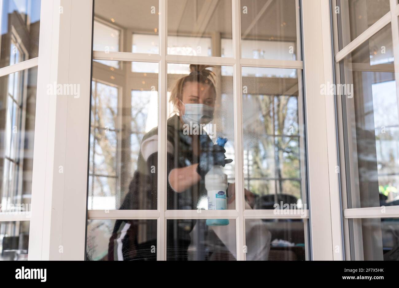 Kiel, Deutschland. April 2021. Ein Mitarbeiter des Cafés 'Wichtig' putzt die Fenster zur Außenterrasse. In Schleswig-Holstein wird eine mögliche Eröffnung der Outdoor-Gastronomie vorbereitet. Quelle: Axel Heimken/dpa/Alamy Live News Stockfoto